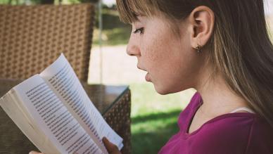 une jeune fille lit un livre à voix haute